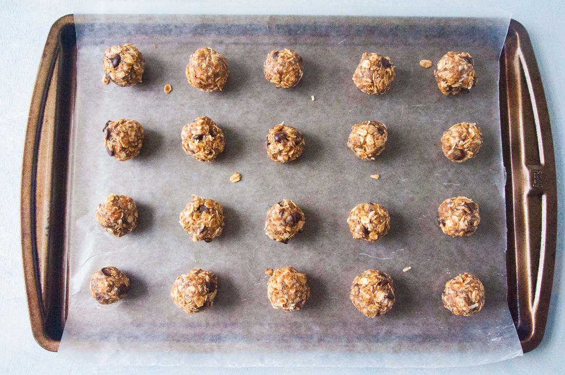 Overview shot of energy bites organized in lines on a lined baking sheet