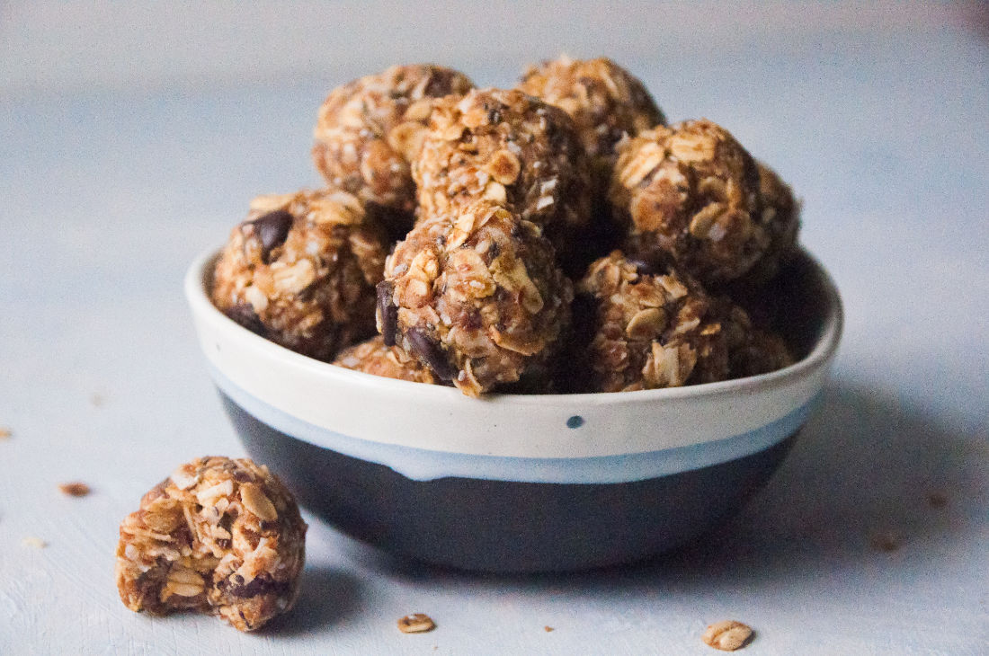 Energy bites piled in a bowl with one out front half eaten