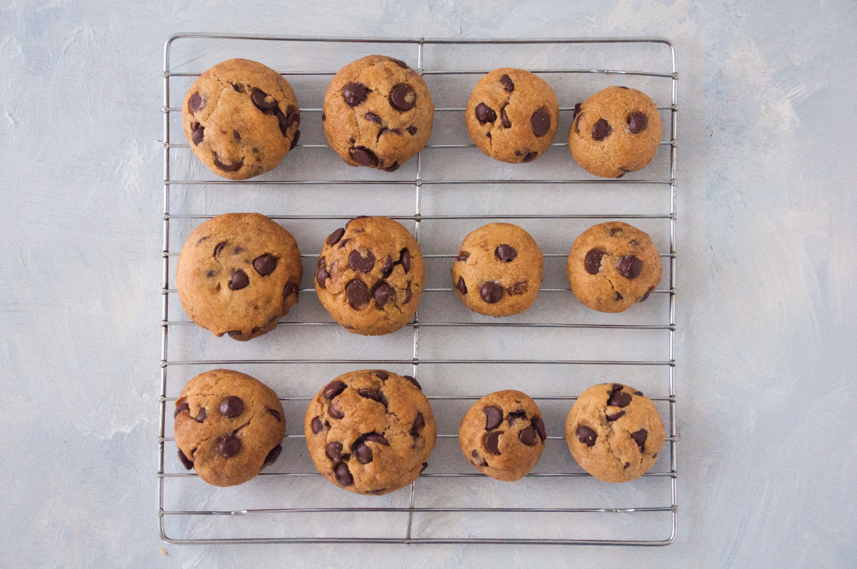 Baked large and small chocolate chip cookies on a cooling rack